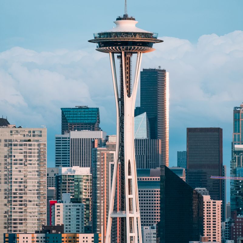 This image features the Space Needle in Seattle, with a backdrop of city skyscrapers and a cloudy sky.